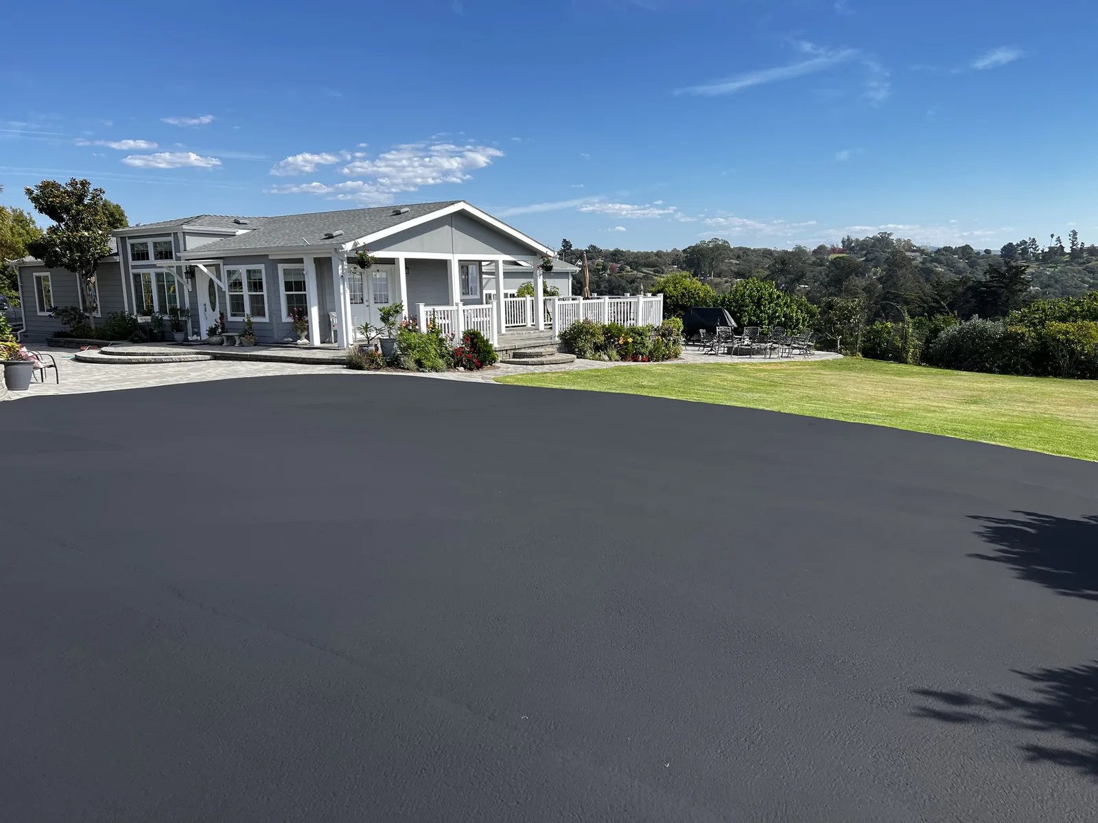 A smooth new black asphalt driveway in front of a ranch style home, asphalt driveway paving