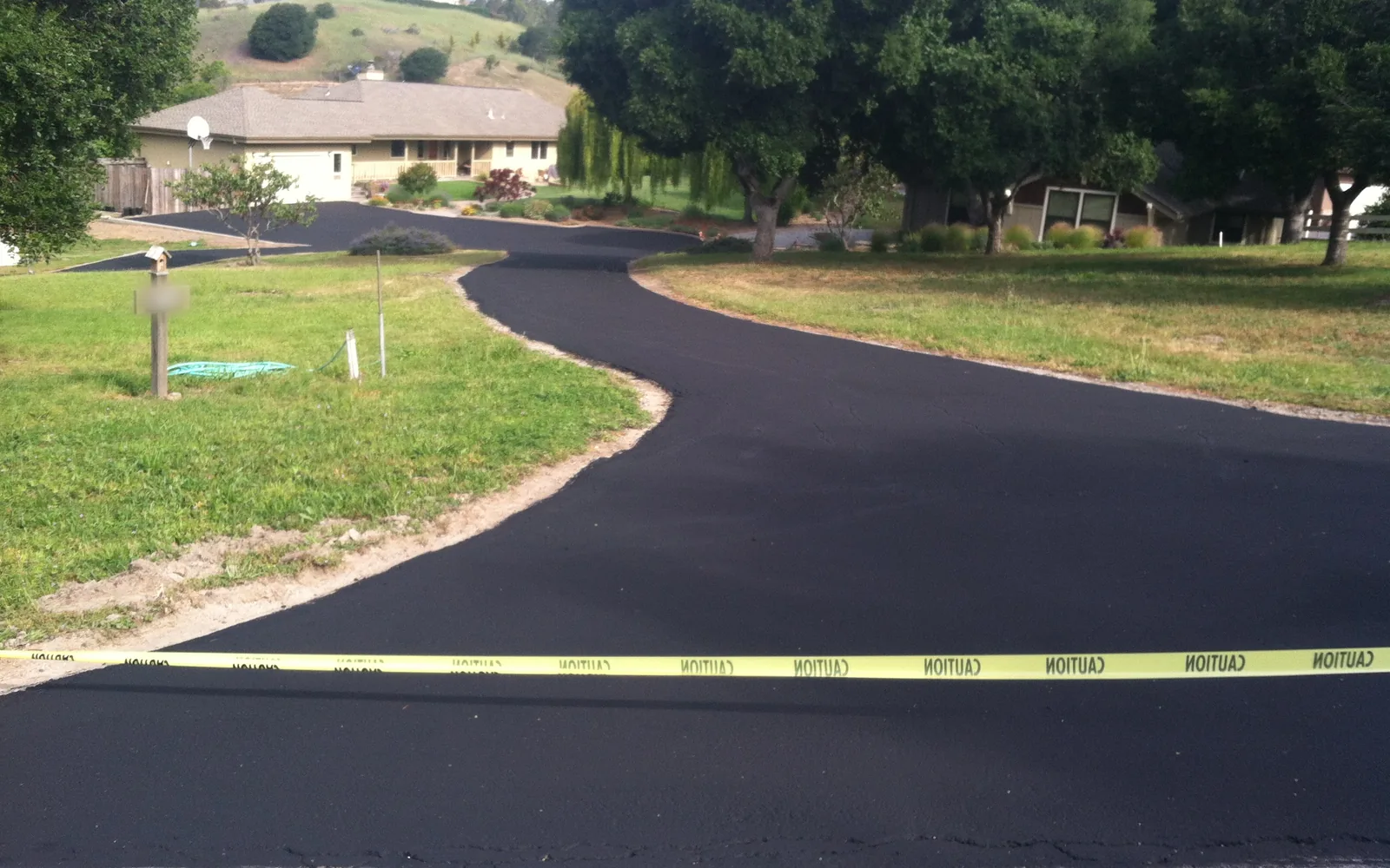 Fresh asphalt driveway winding across a lawn to a ranch style home, asphalt driveway paving
