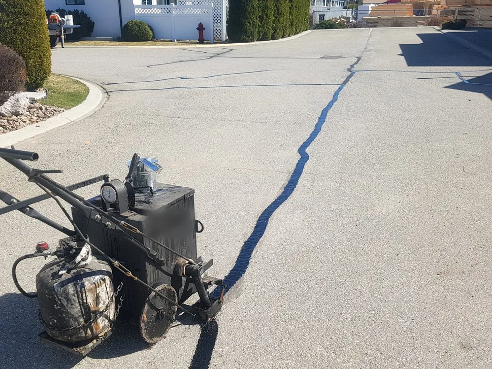 Crack filling machine sealing a long crack across a driveway, asphalt repair