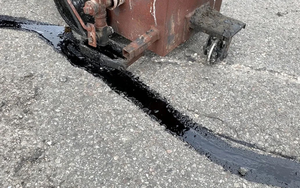 Hot pour crack sealant being applied to cracks in a parking lot, asphalt repair