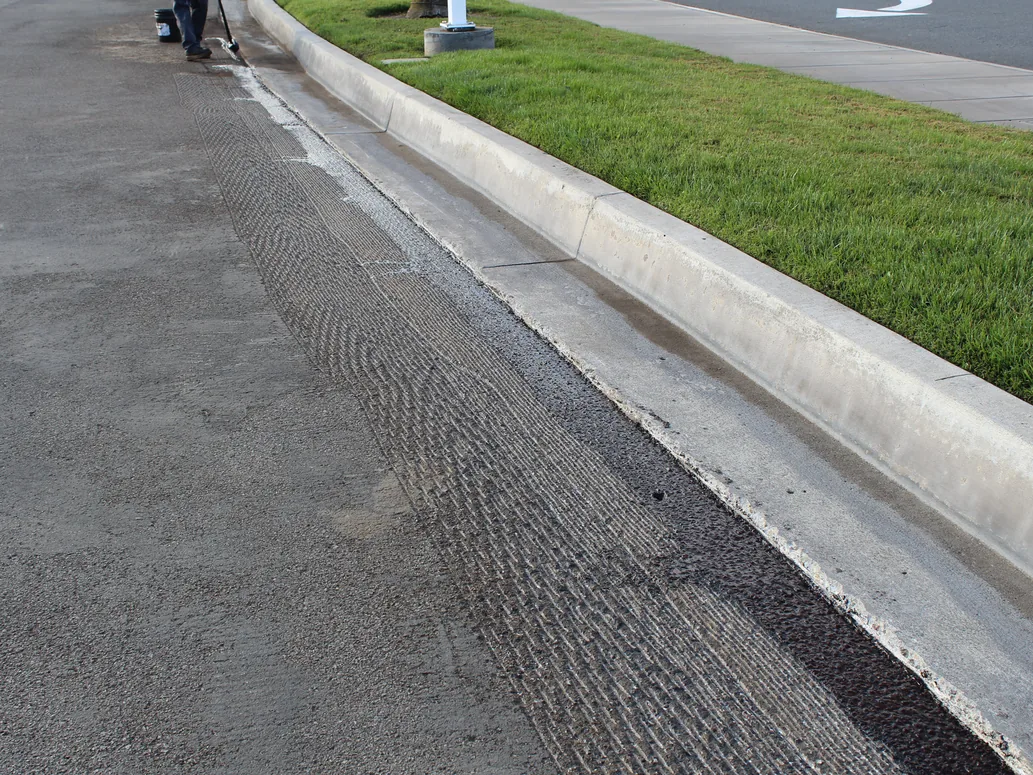 Edge milling cut along a parking lot curb before the overlay, asphalt resurfacing