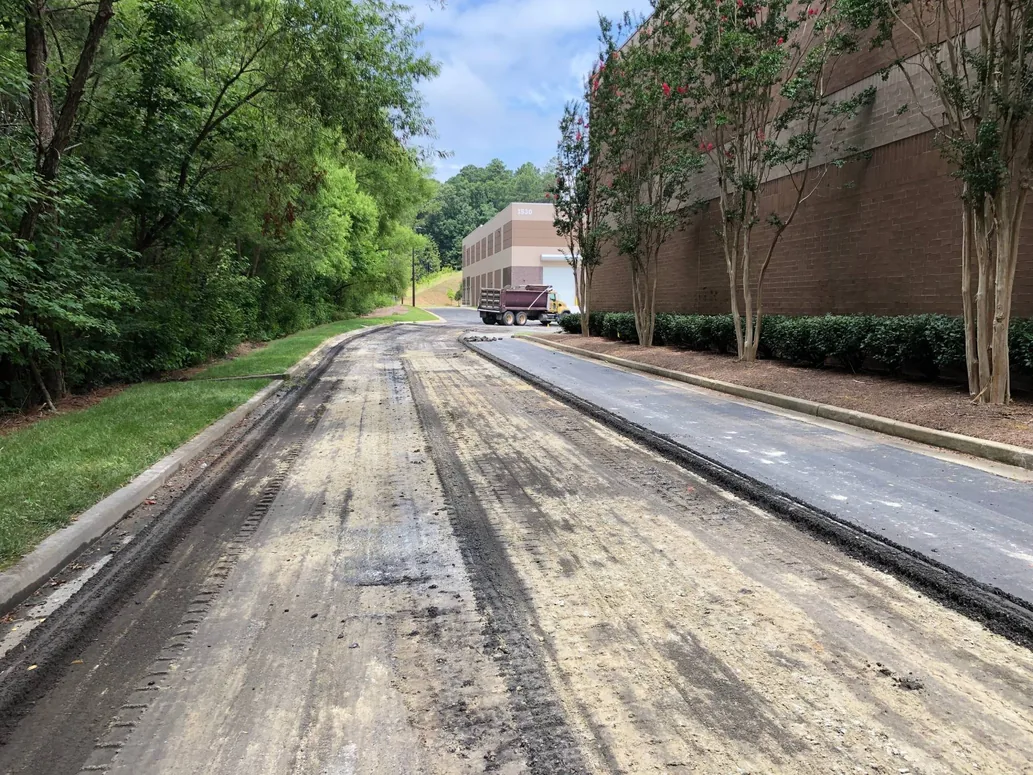 Milled drive lane next to a strip of fresh overlay, asphalt resurfacing