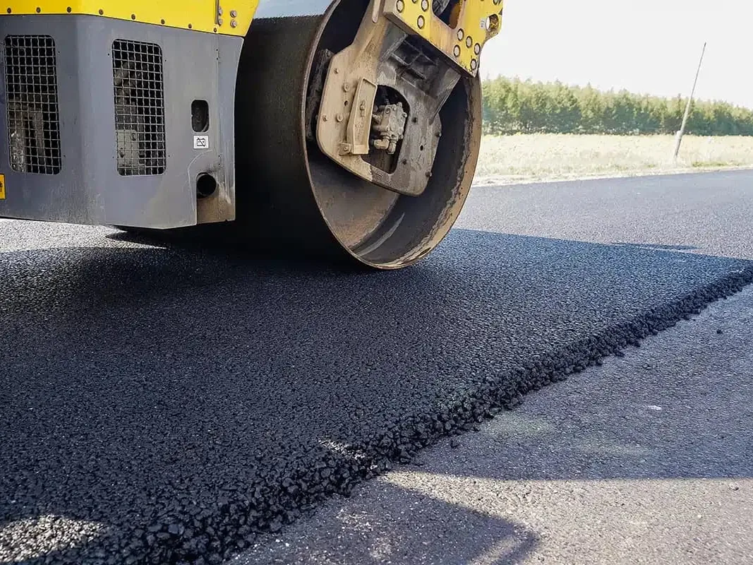 Roller compacting the edge of a fresh asphalt overlay, asphalt resurfacing