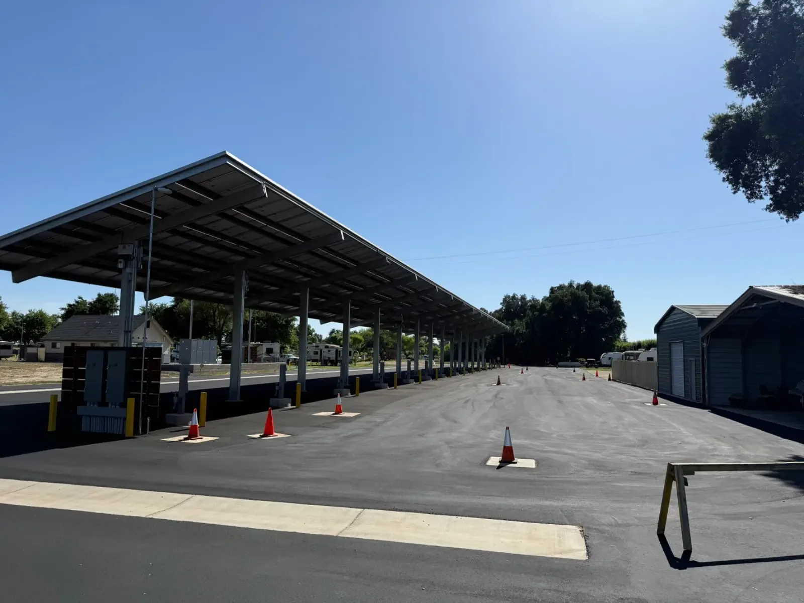 Freshly sealed pavement at a fleet yard with a solar carport, asphalt sealcoating
