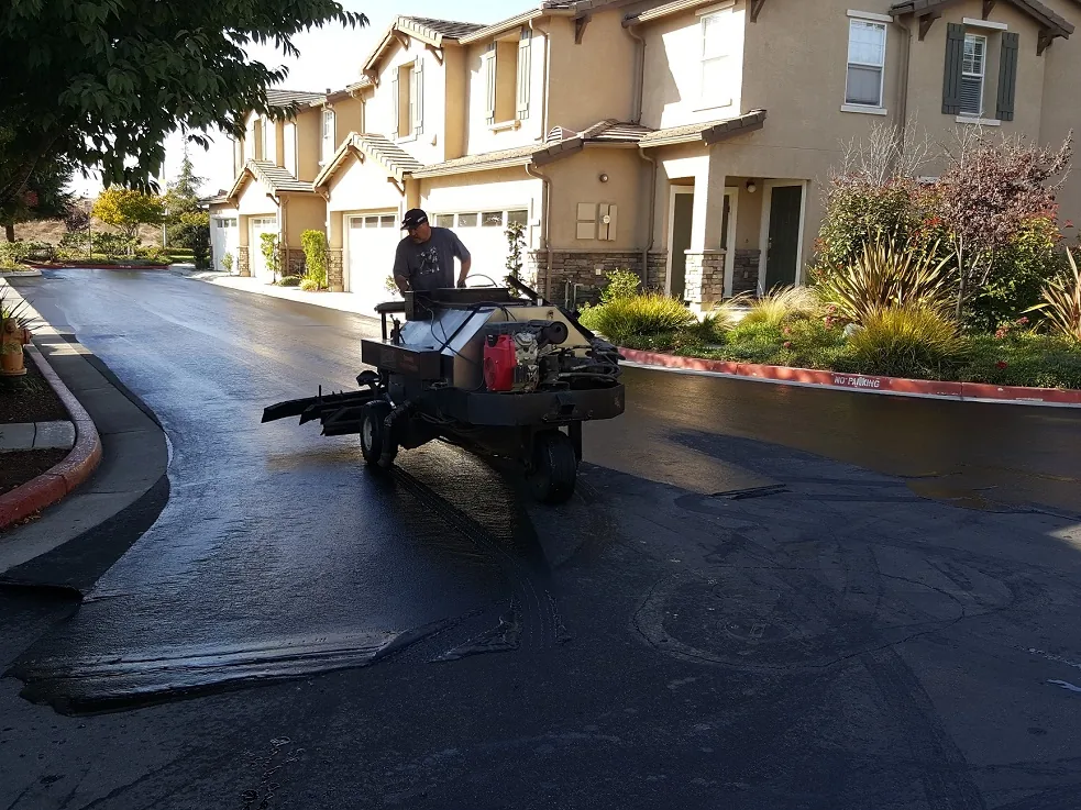 Sealcoat spray rig working a private street between townhomes, asphalt sealcoating
