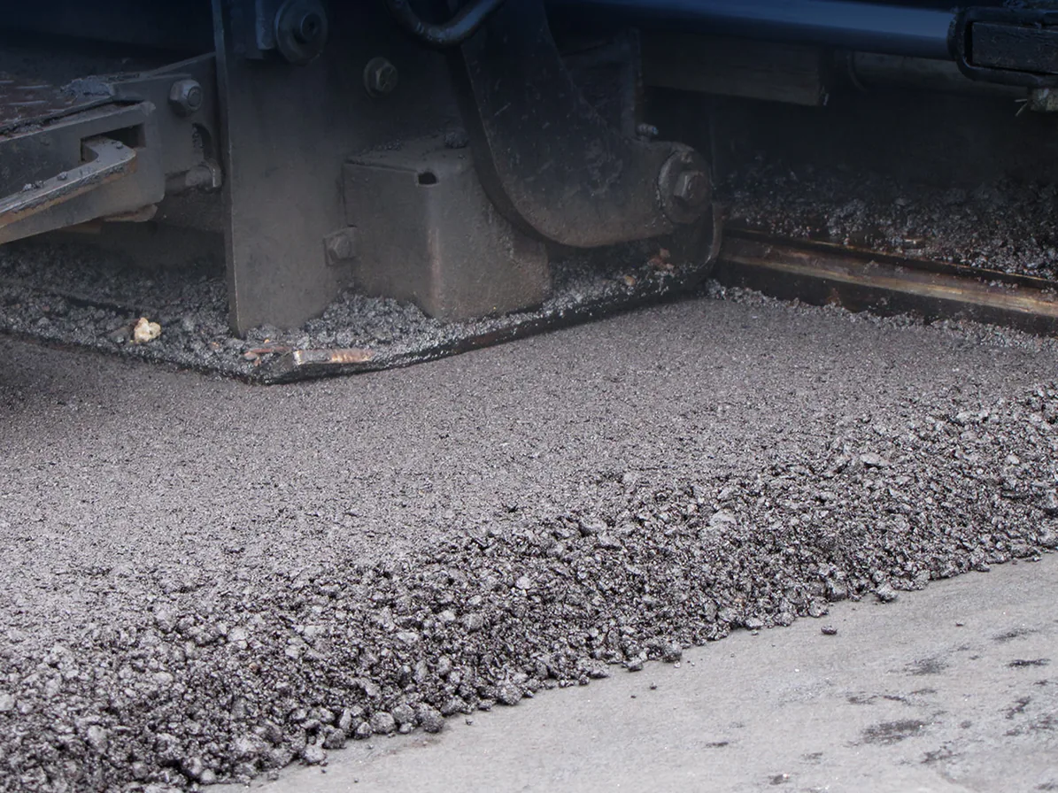 Hot mix asphalt spreading from the paving machine augers, commercial paving