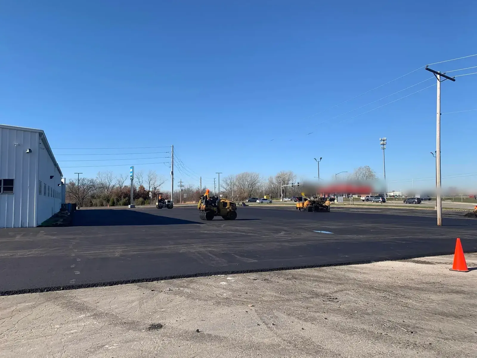 Paving crew and rollers working across a large commercial lot, commercial paving