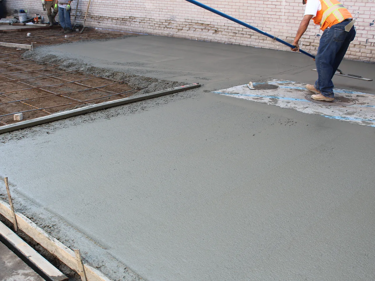 Finishing a fresh concrete pour with a bull float beside rebar, concrete contractor flatwork