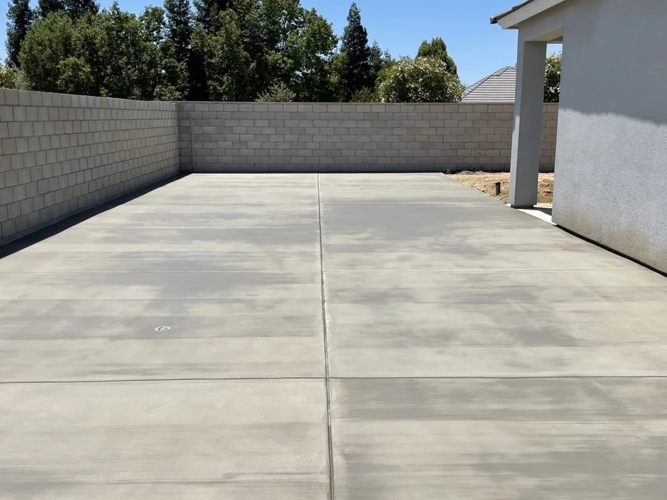 New concrete slab along a block wall in a side yard, concrete contractor flatwork