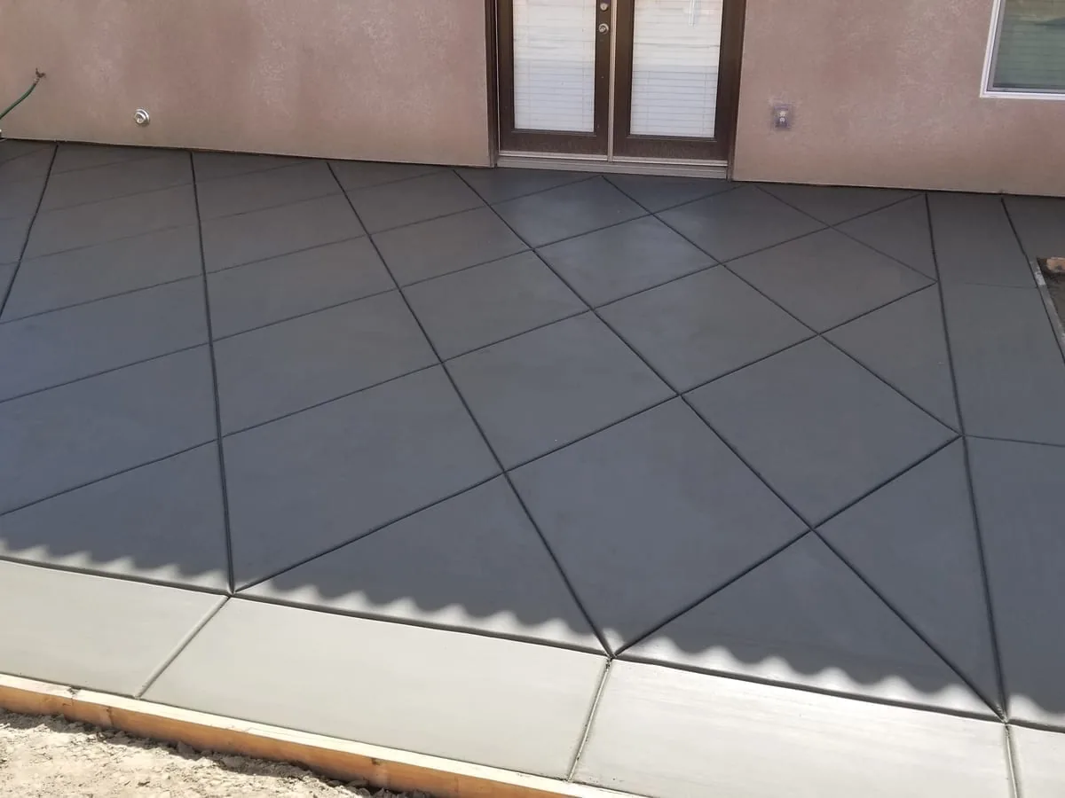 New patio with diagonal control joints behind a stucco home, concrete patios
