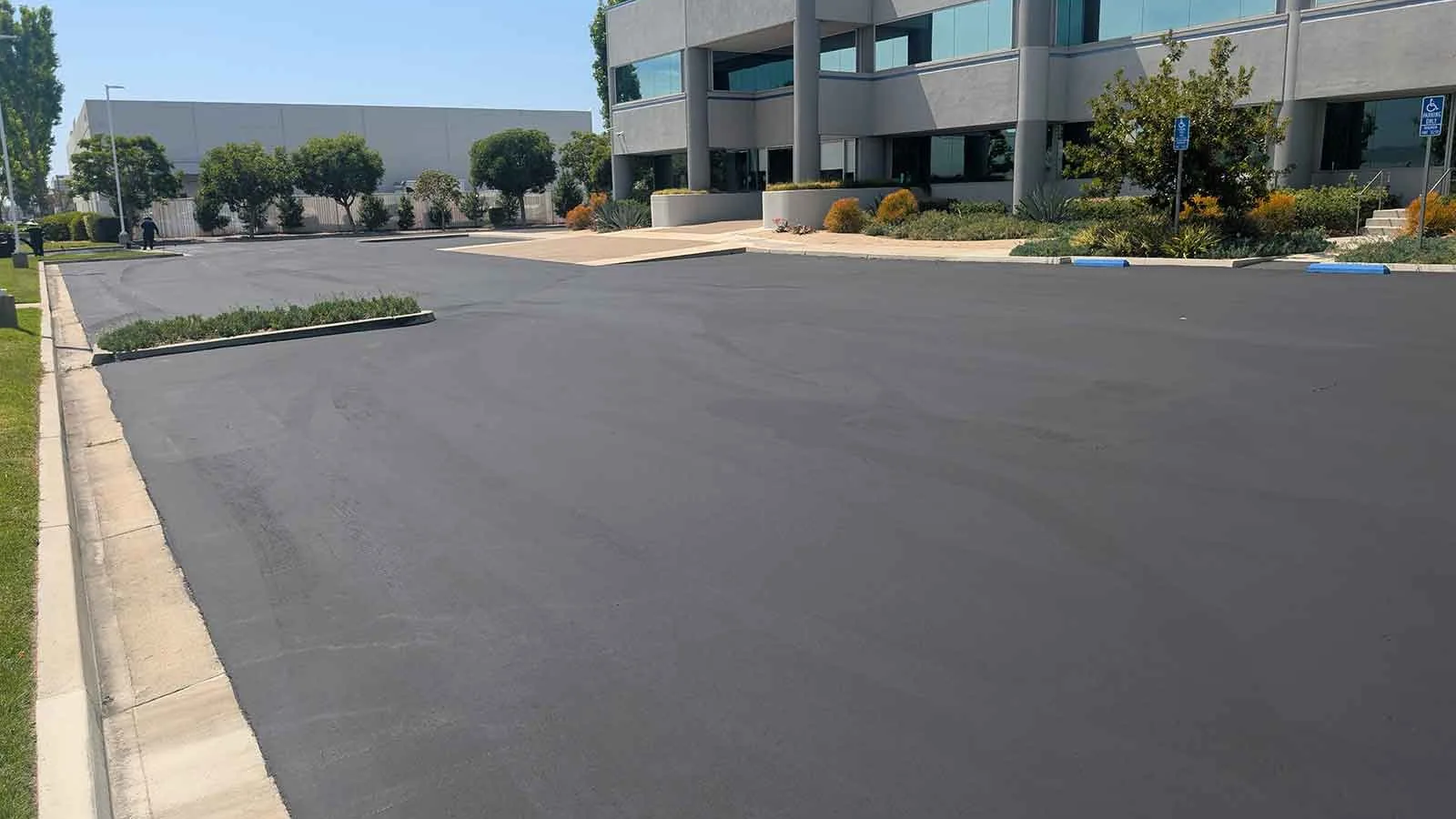 Freshly sealed office parking lot with curbs and planters