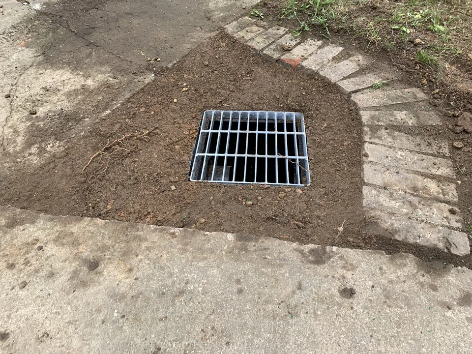 New catch basin grate set level in graded soil, grading drainage work