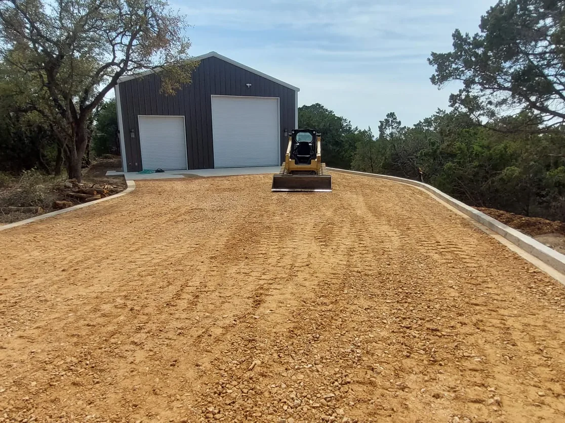 Skid steer grading base rock on a drive to a metal shop, gravel driveways