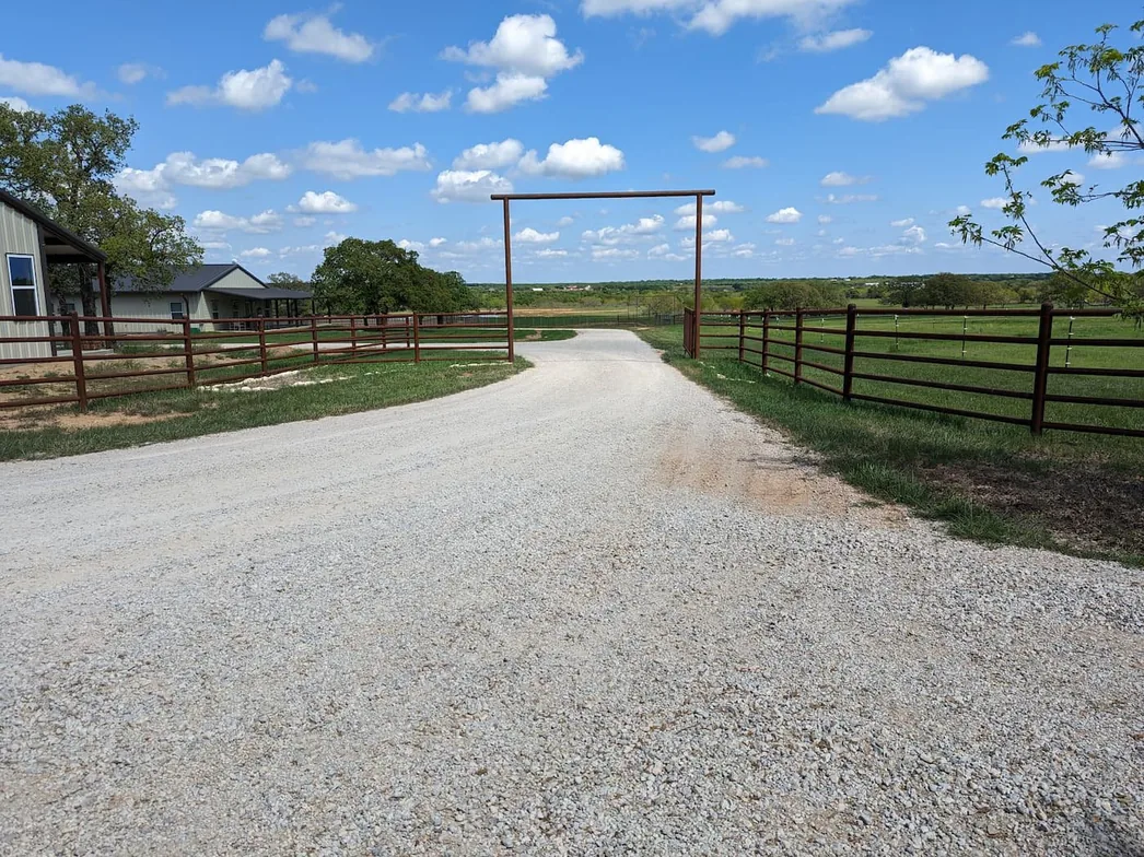Crushed rock ranch drive with pipe fencing and a gate, gravel driveways