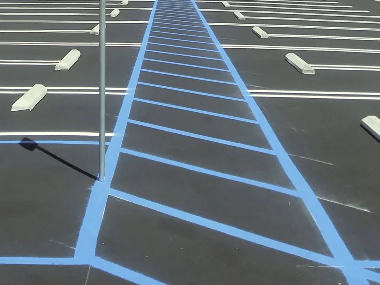 Fresh white stall lines and a blue ADA access aisle in a parking lot, parking lot striping