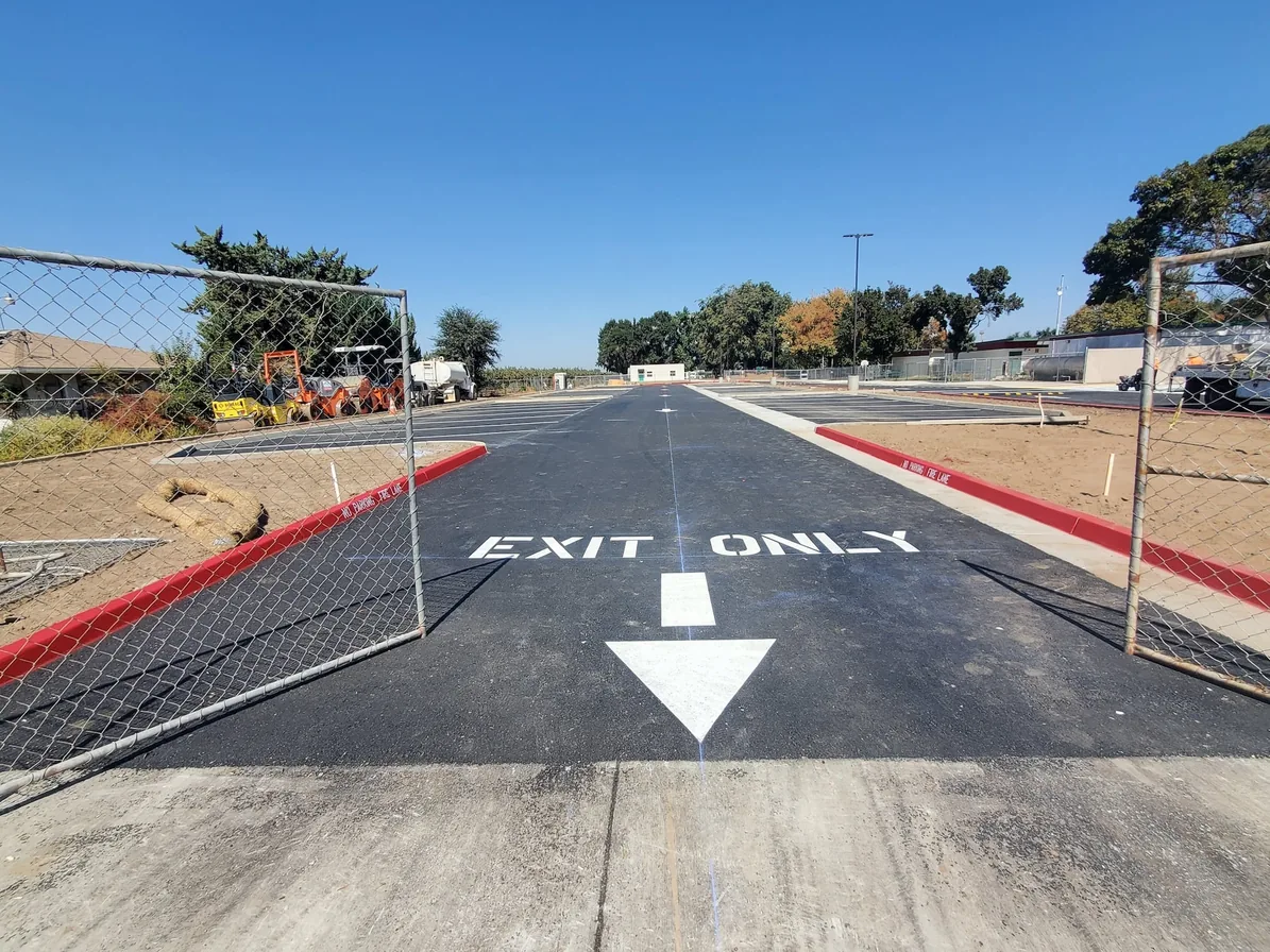 EXIT ONLY lettering and an arrow painted at a lot exit with red curbs, parking lot striping