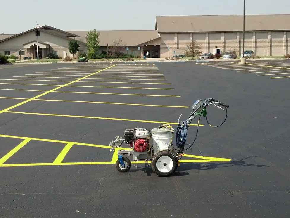 Walk behind striper painting yellow stall lines, parking lot striping
