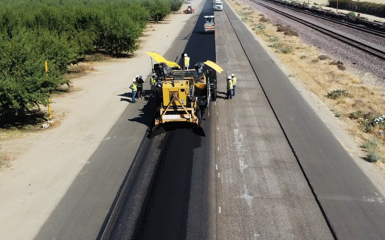 Aerial view of a paving crew laying asphalt along an orchard road, private road paving