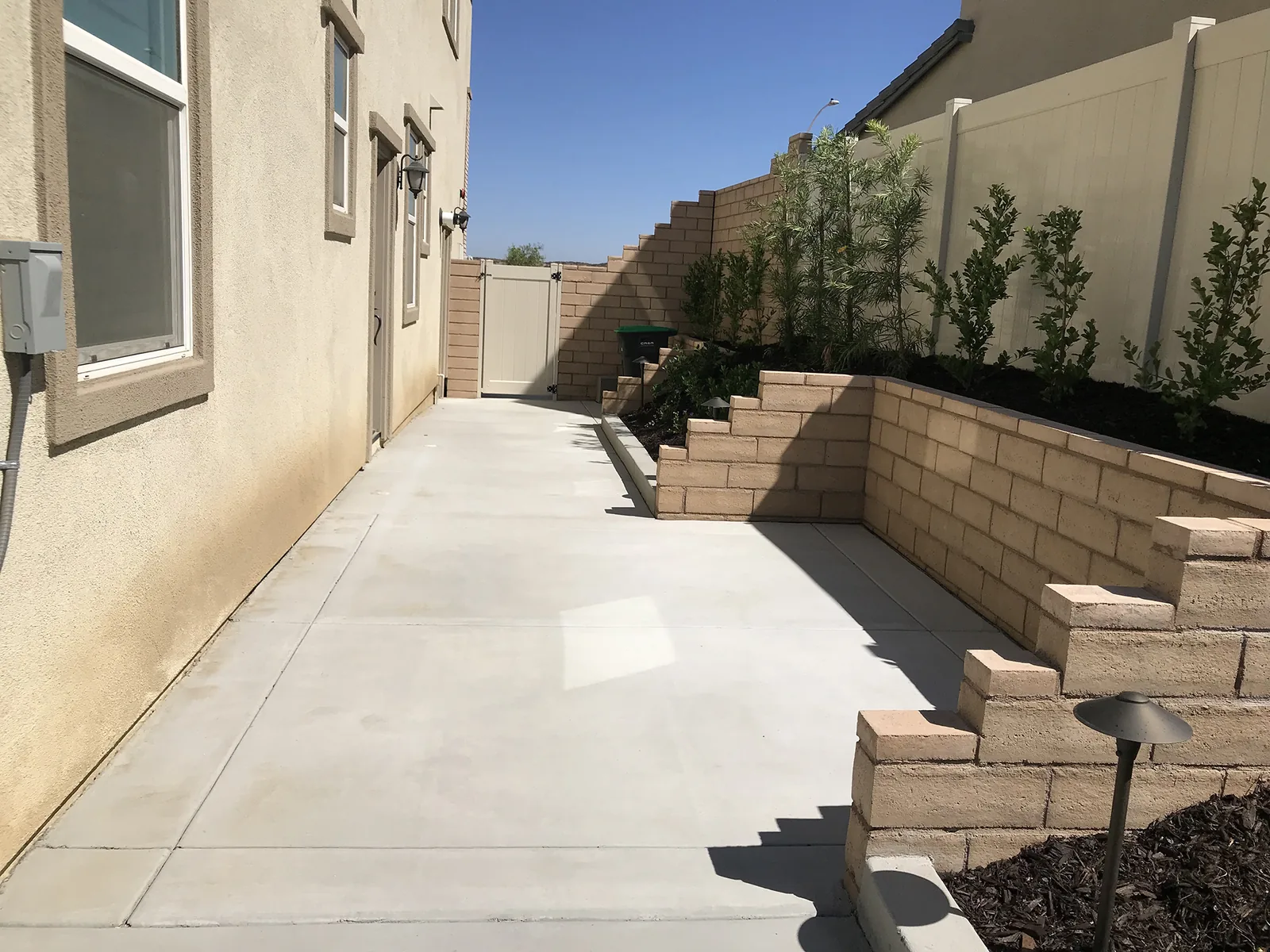 Tan block wall stepping up a side yard slope, retaining walls