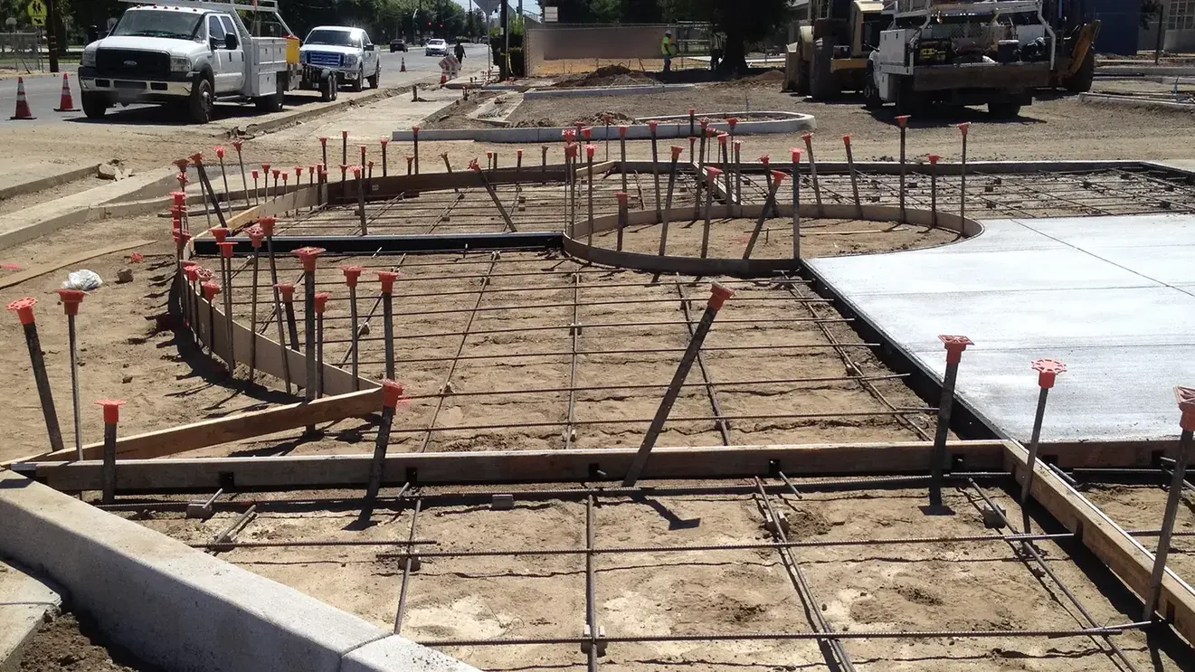 Concrete forms and rebar set beside freshly poured concrete on a commercial site, paving and concrete services